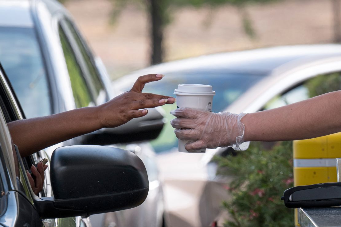 A Starbucks employee hands a customer an order from a drive-thru window in April 2020. 