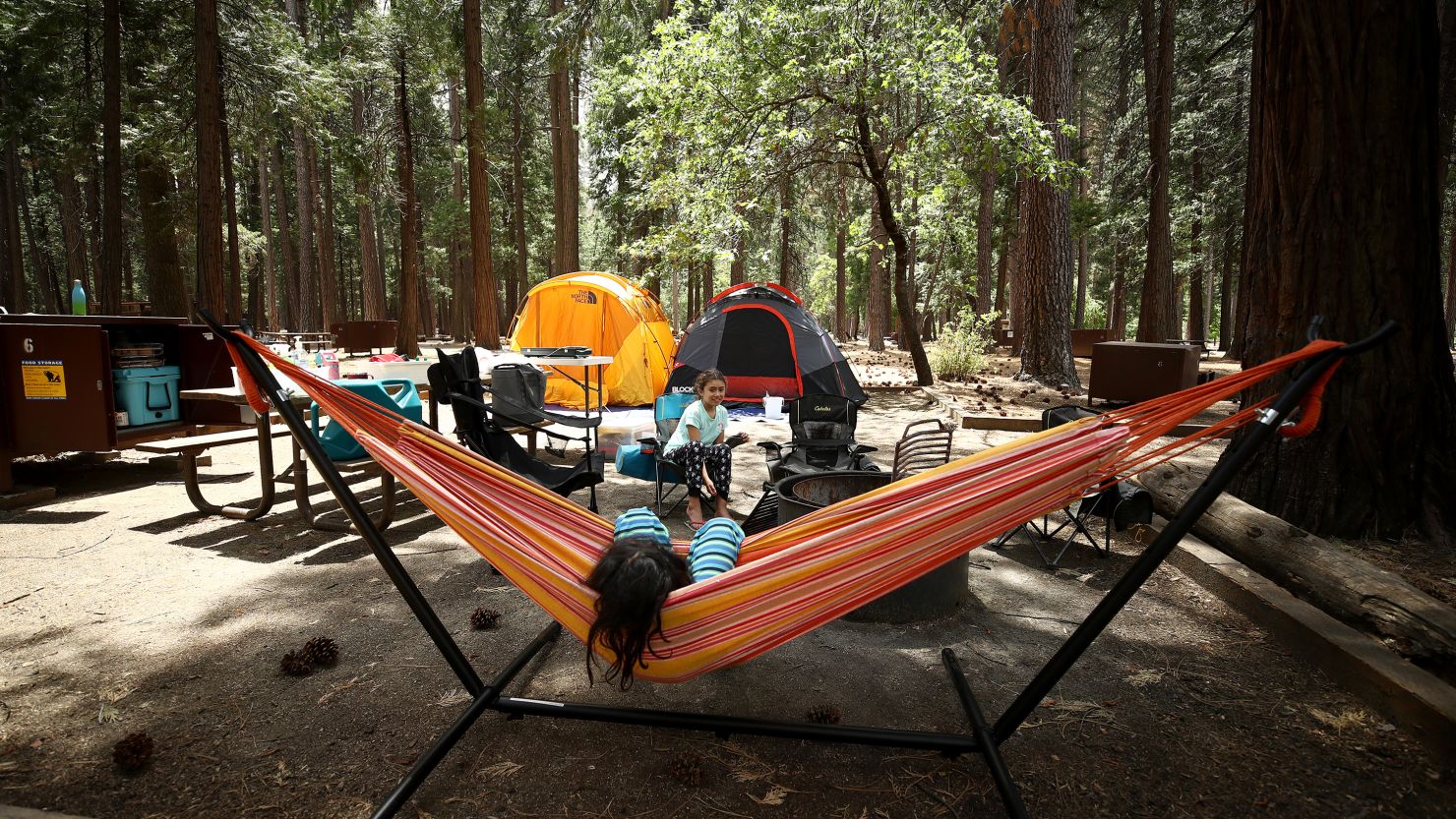 YOSEMITE NATIONAL PARK, CALIFORNIA - JUNE 11: Noah (in hammock) and Valentina Gonzalez from the Sacramento area relax in their campsite on June 11, 2020 in Yosemite National Park, California. Yosemite National Park reopened today with many restrictions after shutting down in March to protect people from COVID-19. Only about half of the average June visitors will be allowed in, and they must make an online reservation for each car. The park will issue 1,700 day passes each day and an additional 1,900 passes for reservations at campsites or hotels in the park. (Photo by Ezra Shaw/Getty Images)