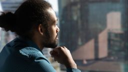Close up of pensive African American man look in window distance thinking or pondering of future career opportunities. Thoughtful ethnic male make decision or plan. Business vision concept.