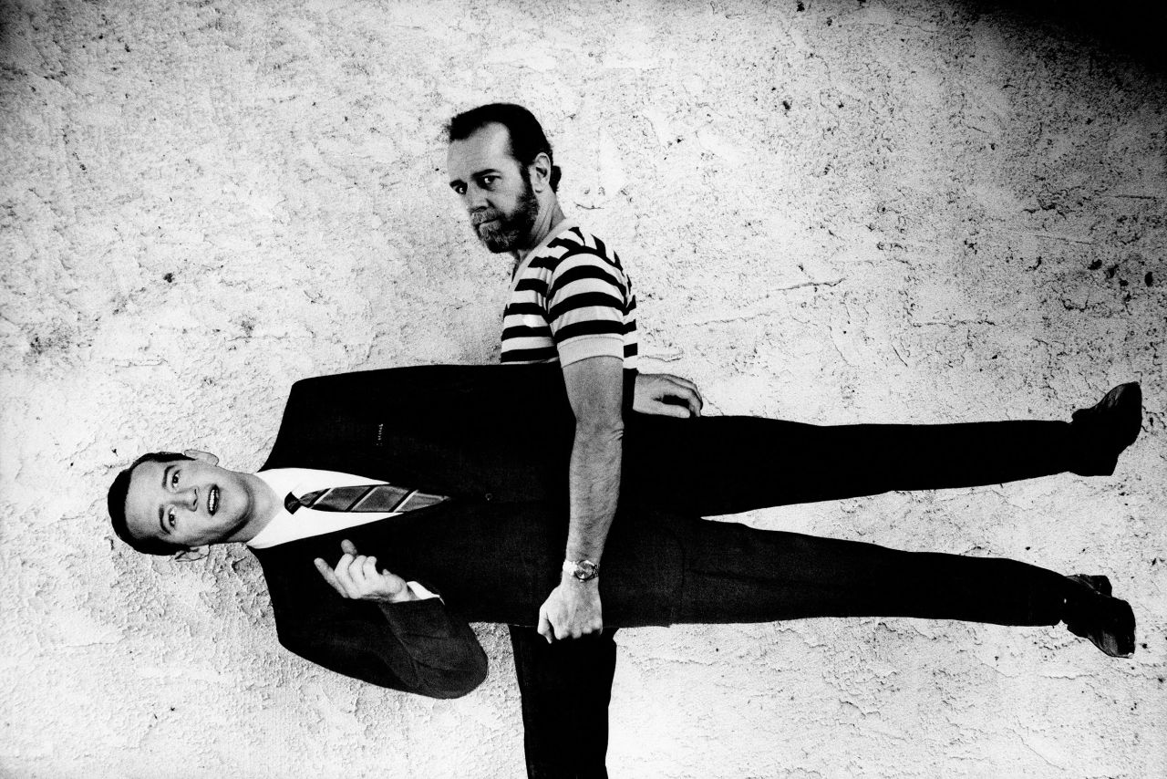 Comedian George Carlin holds a cardboard cutout of his younger self.