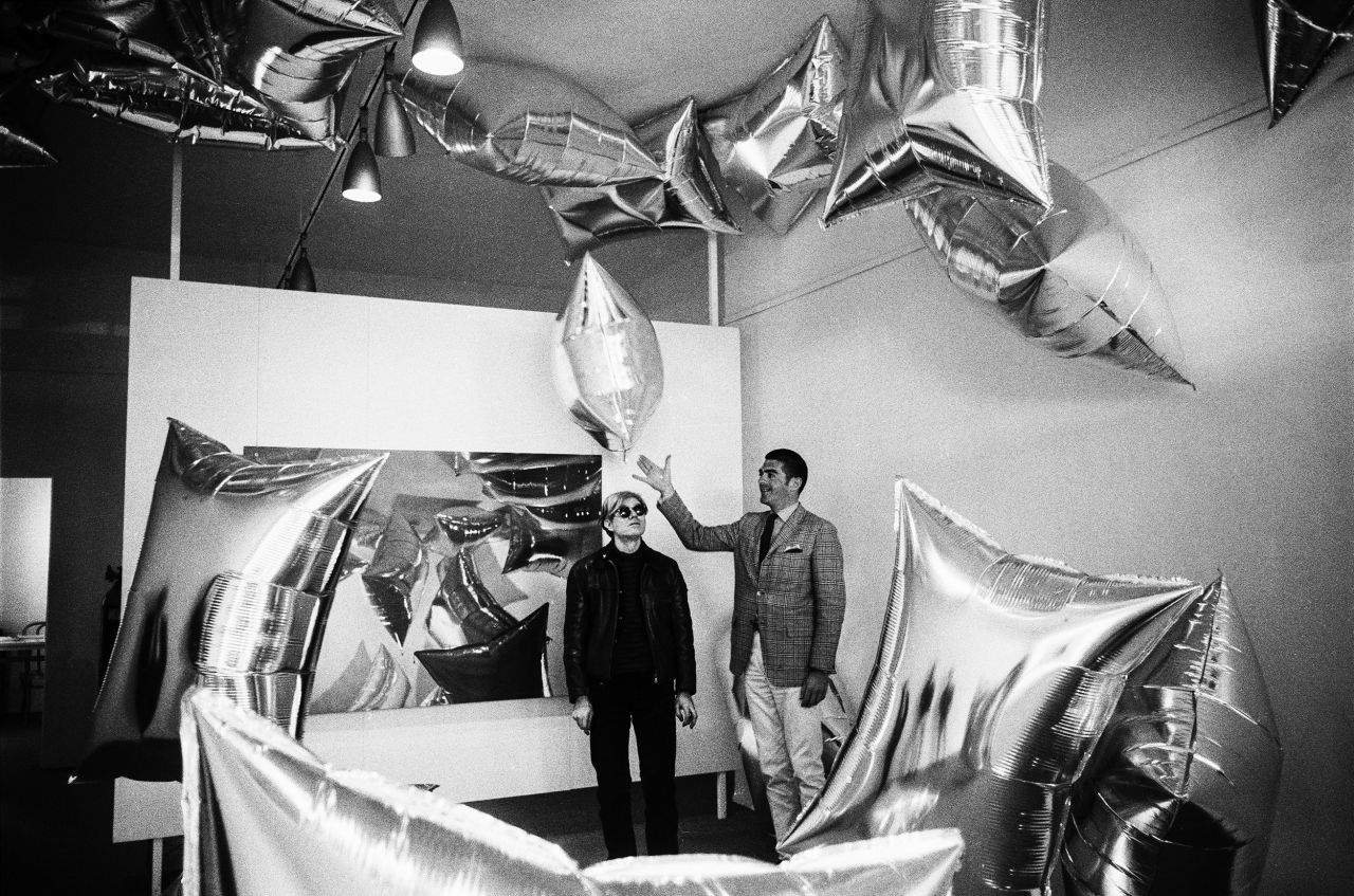 Artist Andy Warhol, left, and art dealer Irving Blum stand amid Warhol's "Silver Clouds" installation at the Ferus Gallery in Los Angeles in 1966.