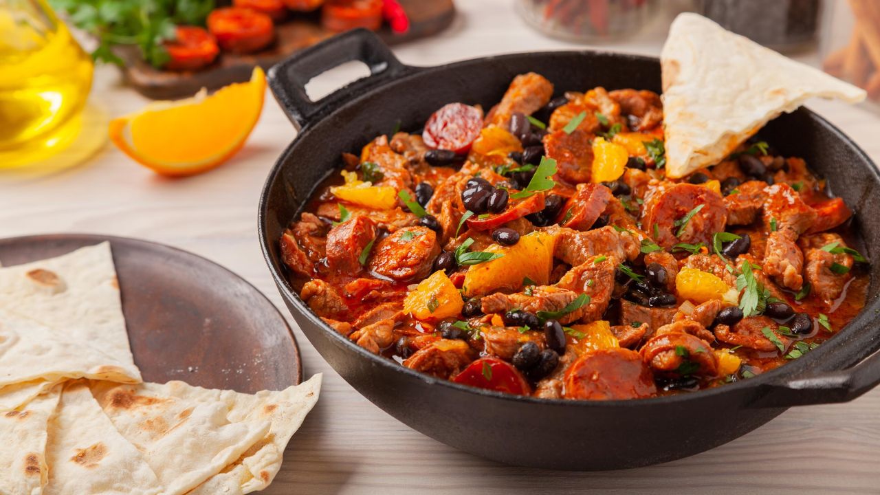 This spicy pork stew with chorizo and black beans is perfect served with tortillas and orange slices.