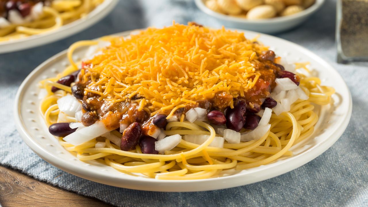 Cincinnati chili is prepared with warming spices, spaghetti, and a generous helping of shredded cheddar.