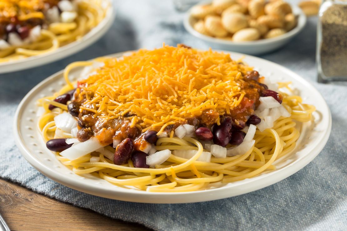 Cincinnati chili is prepared with warming spices, spaghetti, and a generous helping of shredded cheddar.