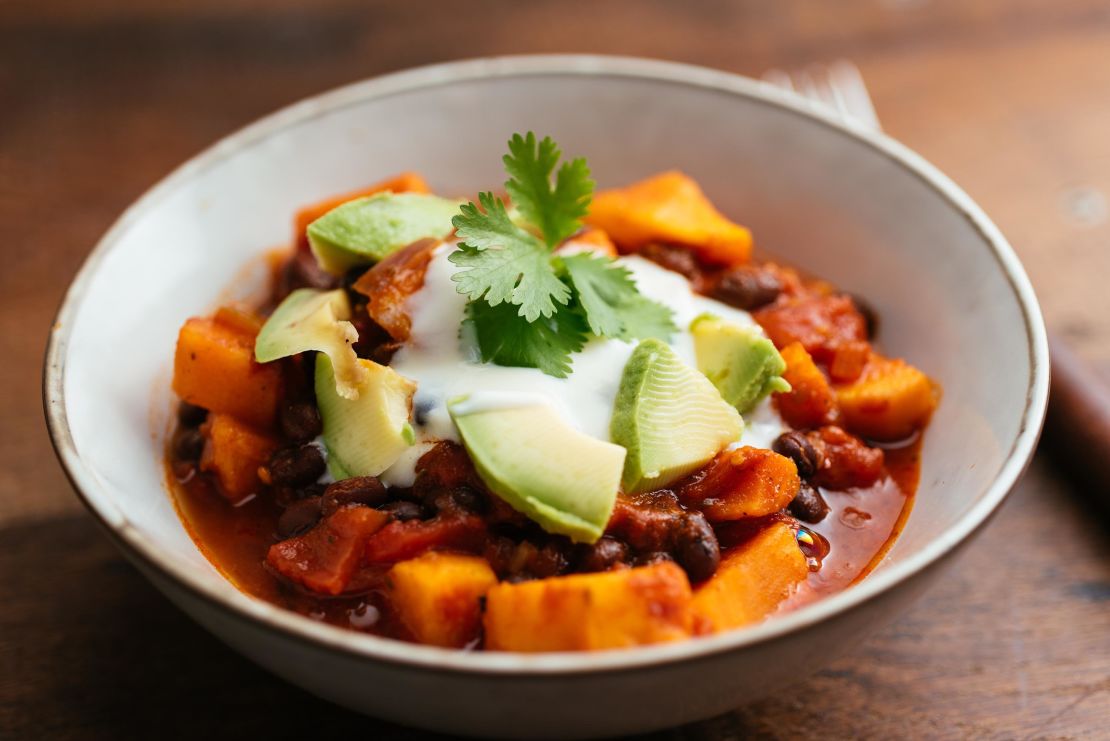 This vegan chili, made with sweet potatoes and black beans, is topped with soy yogurt and avocado.