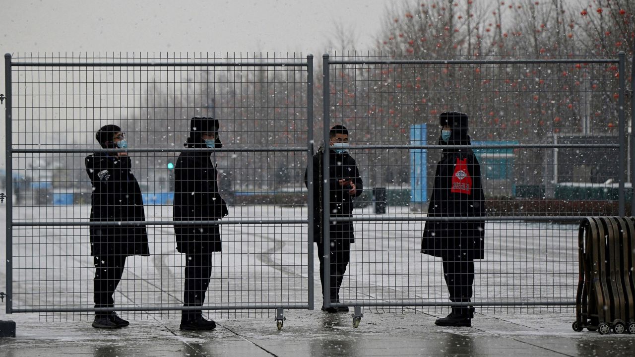 Security personnel stand behind a fence at the Olympic Park in Beijing, two weeks before the start of the 2022 Winter Olympic.