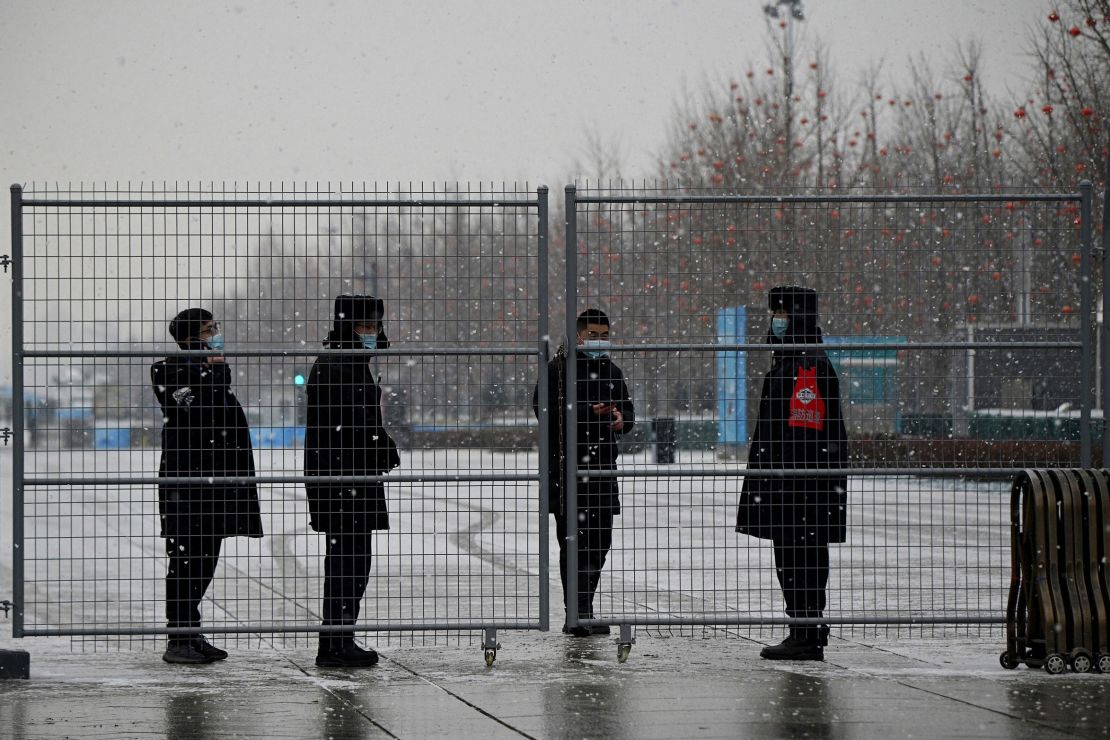 Security personnel stand behind a fence at the Olympic Park in Beijing, two weeks before the start of the 2022 Winter Olympic.