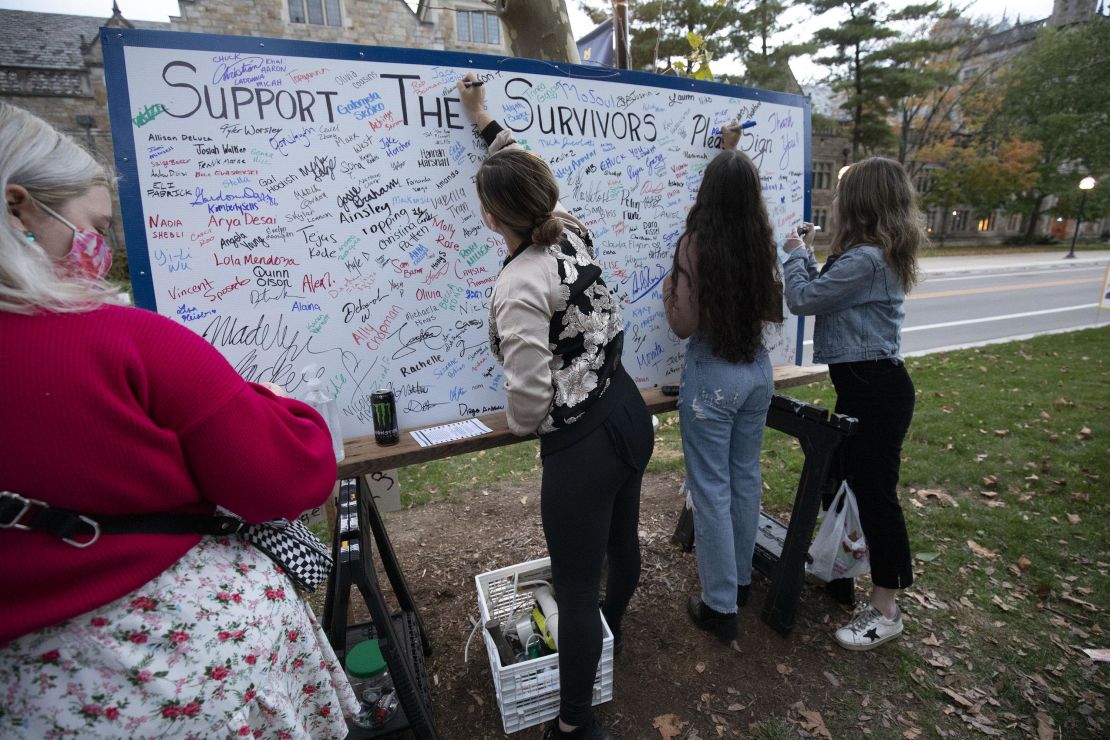 Attendees add their signatures to a board in support of survivors of sexual abuse at a vigil outside the home of outgoing University of Michigan President Mark Schlissel October 13, 2021 in Ann Arbor, Michigan.