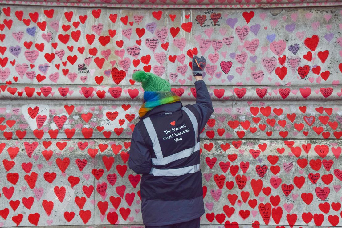 A volunteer paints hearts on the UK's National Covid-19 Memorial Wall.