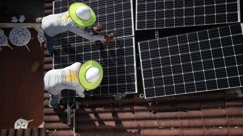 Roger Garbey (top) and Andres Hernandez, from the Goldin Solar company, install a solar panel system on the roof of a home on January 23, 2018, in Palmetto Bay, Florida. 