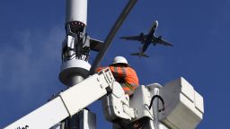 A contractor installs 5G cellular equipment on a light pole as a Delta Air Lines, Inc. Airbus A320 airplane lands at Los Angeles International Airport (LAX) in Inglewood, California, on January 19.