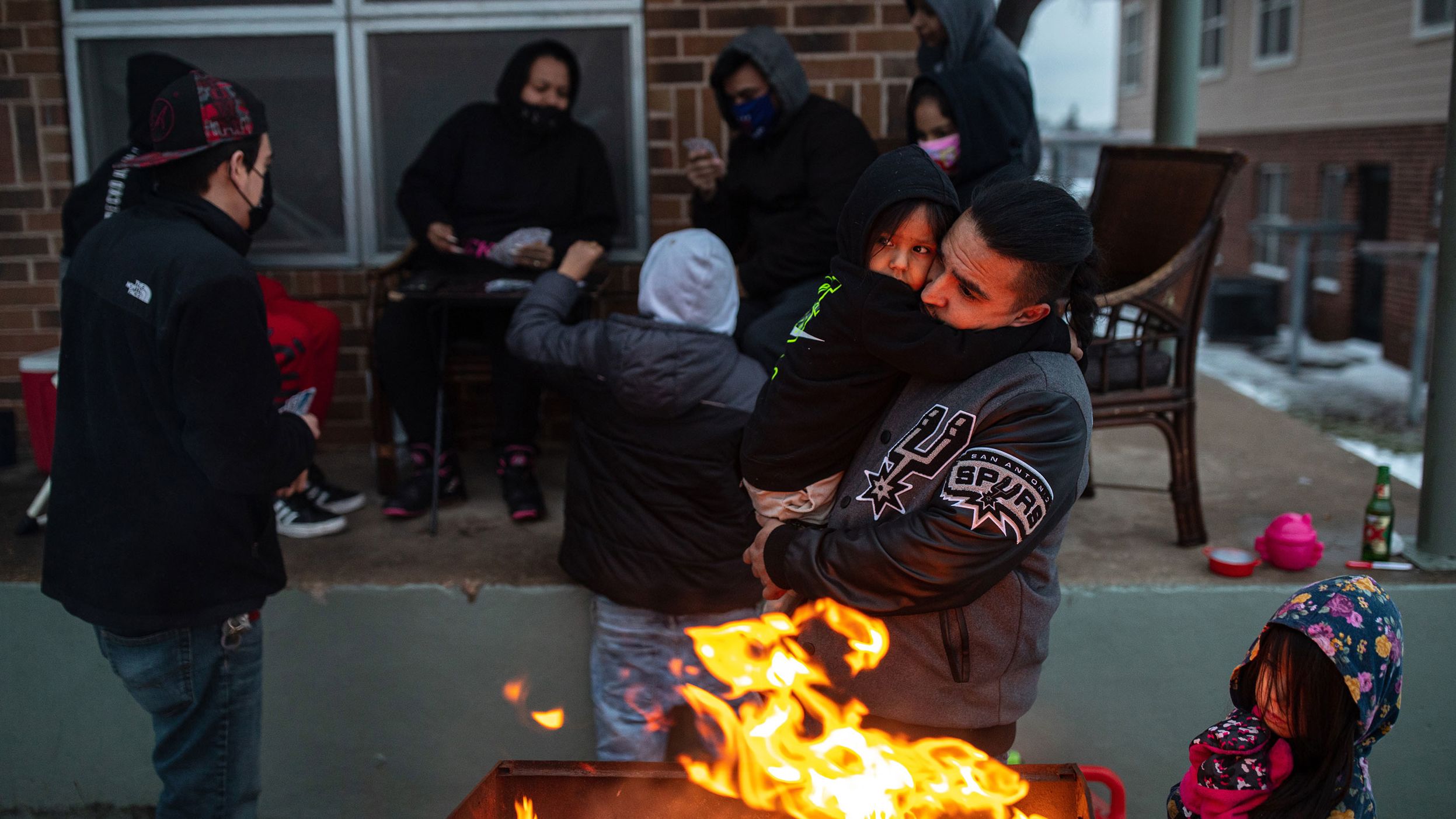 Eric Traugott warms up his young son, Eric Jr., beside a fire outside of their apartment in Austin, Texas, in February 2021. A brutal cold snap that month left millions in the dark and without heat. 