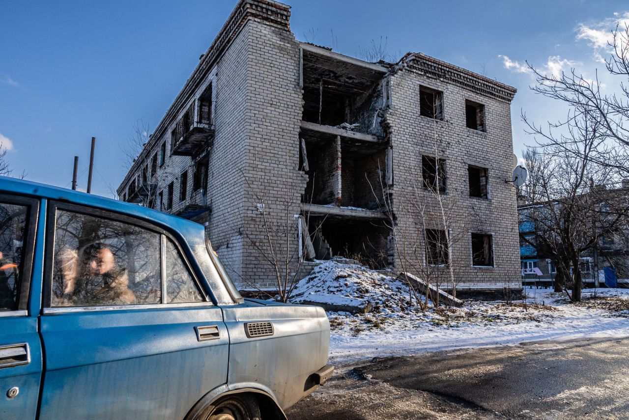 Local residents drive past an apartment building in Marinka. The building was badly damaged during fighting in 2015 between the Ukrainian army and Russian-backed separatists.
