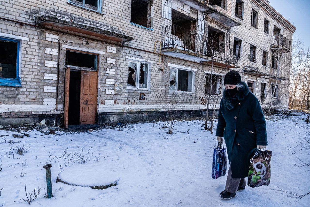 A woman walks past a damaged apartment building in Marinka. "The mood was somber, depressed and resigned," Fadek said. "People are going through the motions of their daily lives."