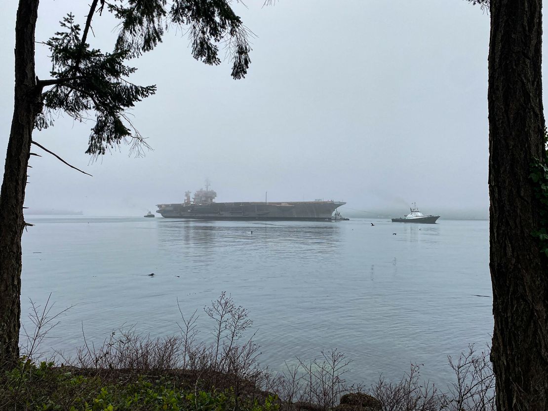 Navy tug boats support the ex-USS Kitty Hawk's in its final transit from Naval Base Kitsap-Bremerton, Washington to a shipbreaking facility in Texas.