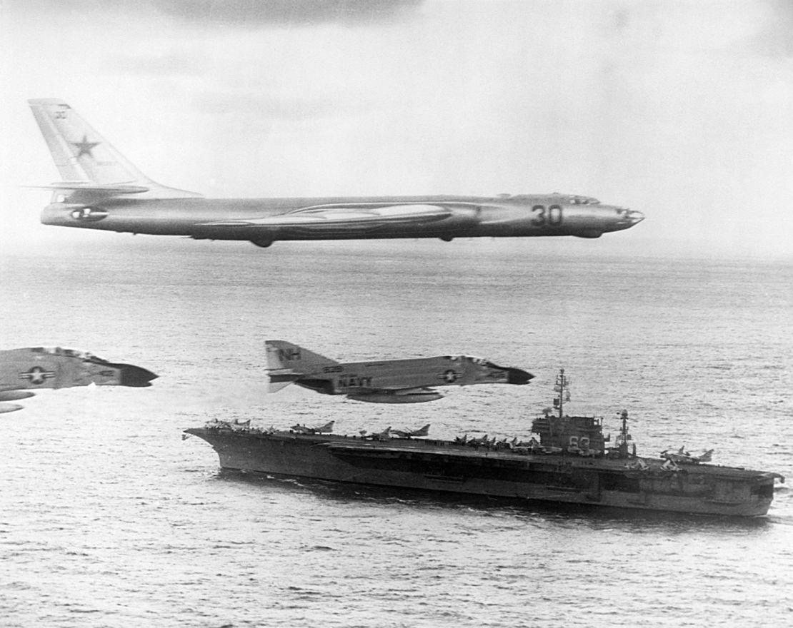 A Russian-made Tupolev TU-16 Badger-A surveillance bomber flies with US Navy escort fighters over the attack carrier USS Kitty Hawk during Cold War activities over the North Pacific Ocean in January of 1963. 