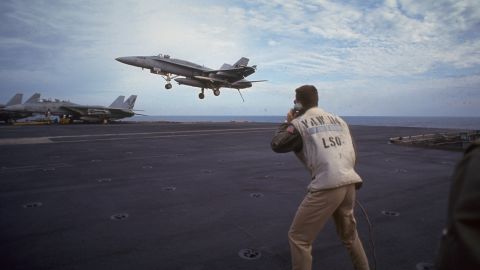 Crew watching a fighter jet landing on USS Kitty Hawk during a US-led allied air strike on Iraq, reinforcing UN post-Gulf War resolutions on January 19, 1993.