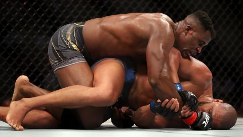 Ngannou grapples on the ground with Gane. 