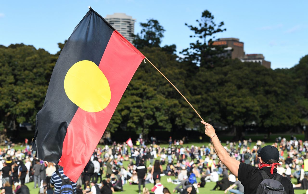 A man holds the Aboriginal flag at a rally in Sydney, Australia.