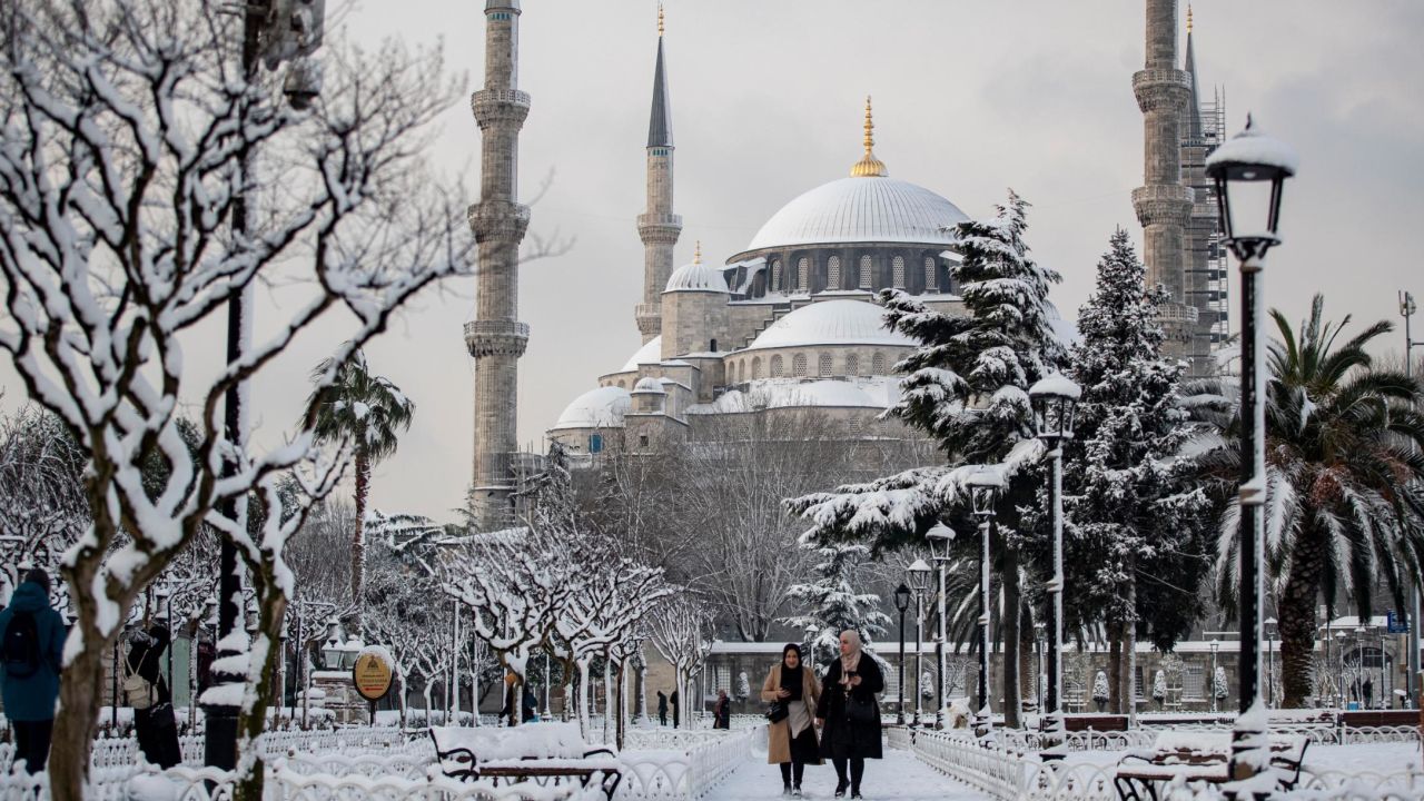 People walk in front of Istanbul's snow-dusted Blue Mosque.