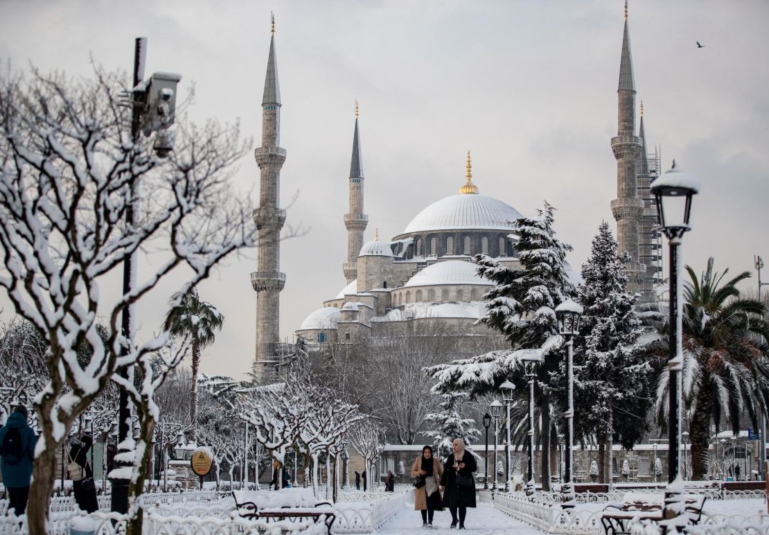 People walk in front of Istanbul's snow-dusted Blue Mosque.