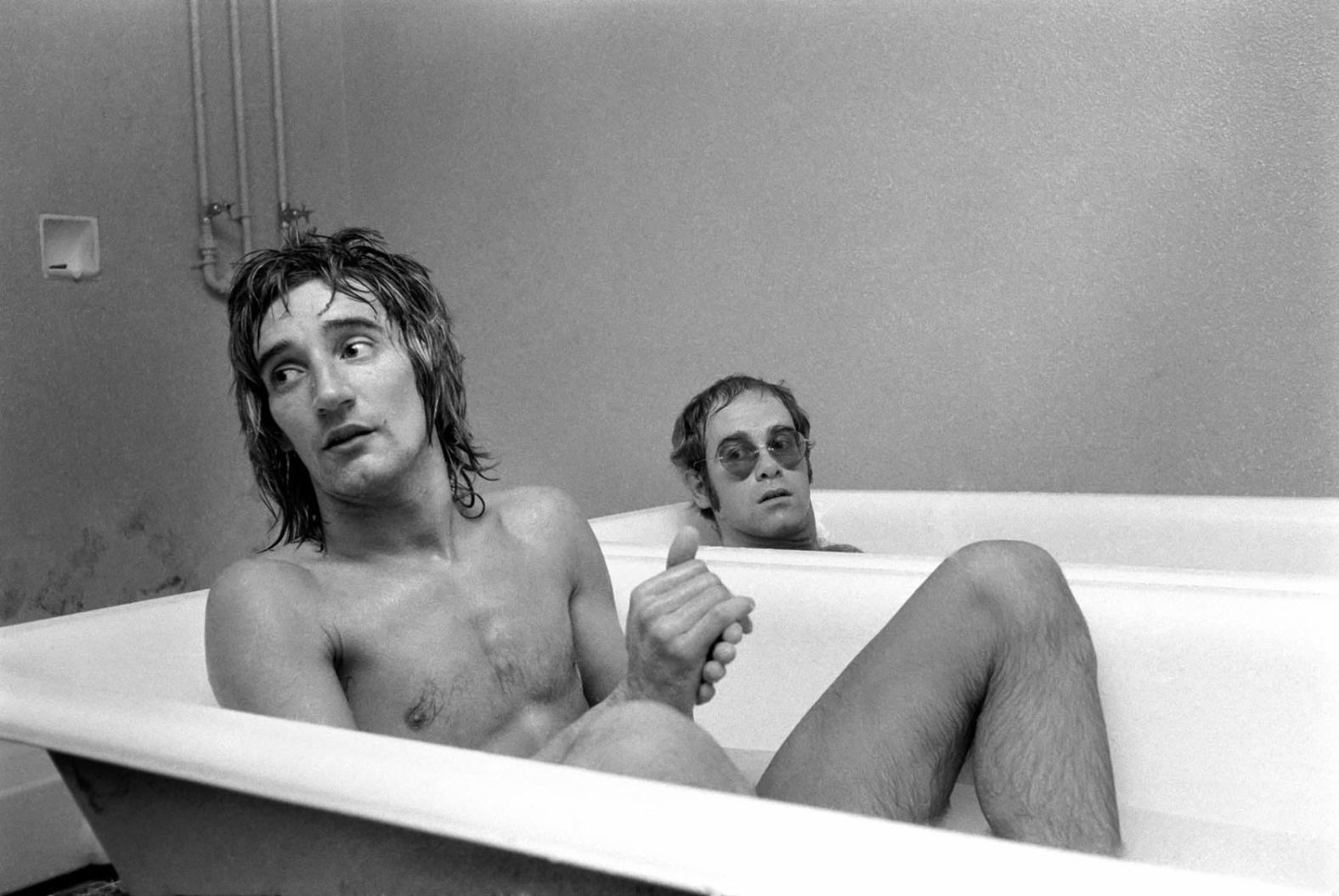 John and singer Rod Stewart have a bath at the stadium of Watford Football Club in 1973. John, a lifelong Watford fan, later owned the English soccer club. Today, one of the stadium's stands is named after him.