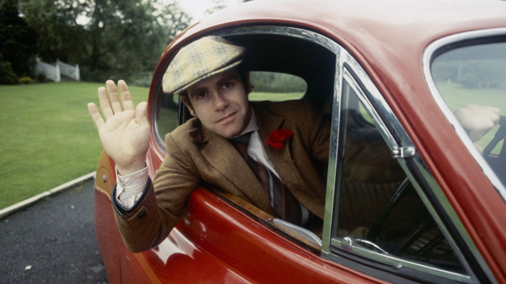 John waves from his car in 1978.