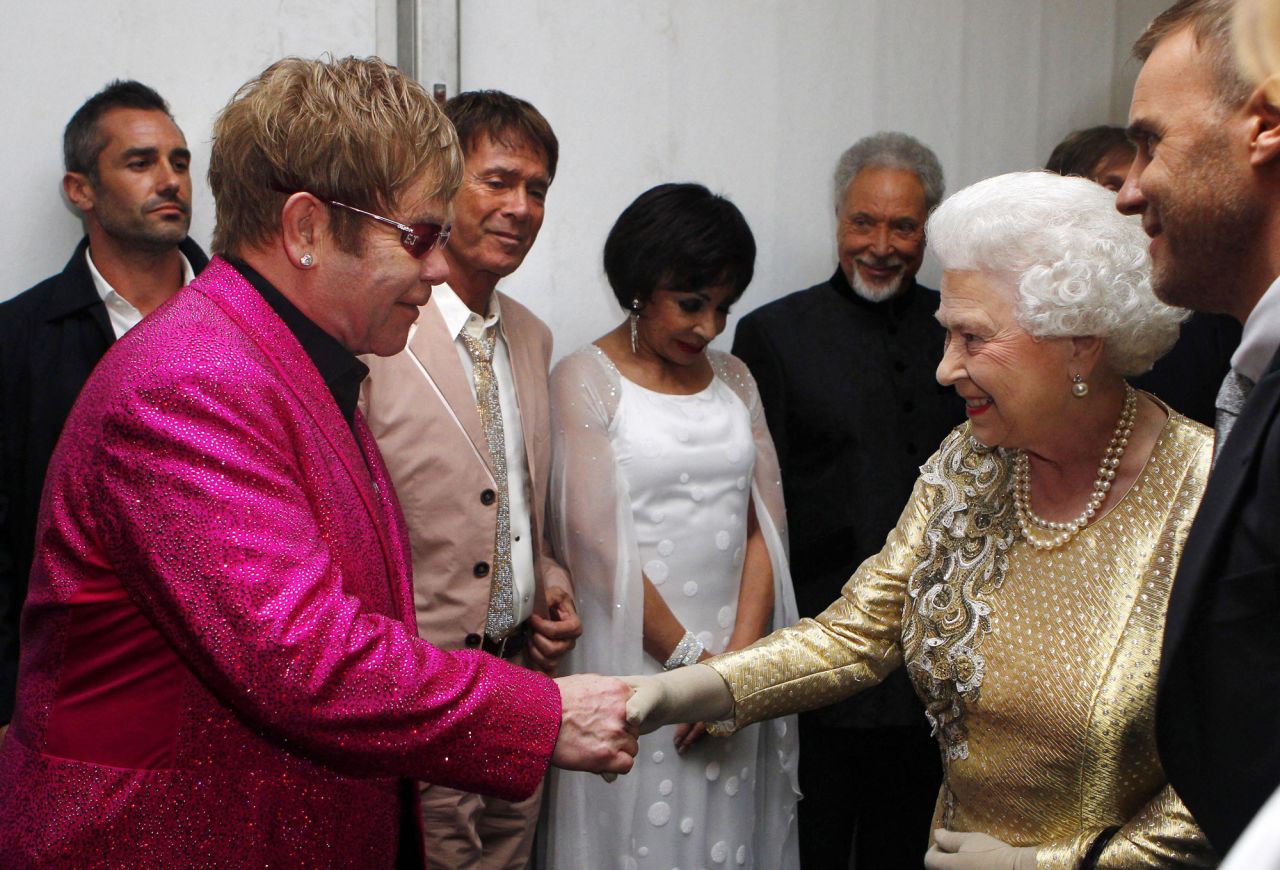 Britain's Queen Elizabeth II shakes hands with John at her Diamond Jubilee Concert in 2012. In 1998, the Queen knighted John for his music and charity work.