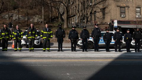 New York City police officers and firemen stand at attention as they await the remains of Police Officer Jason Rivera to be brought to the funeral home on January 23 in New York City. 