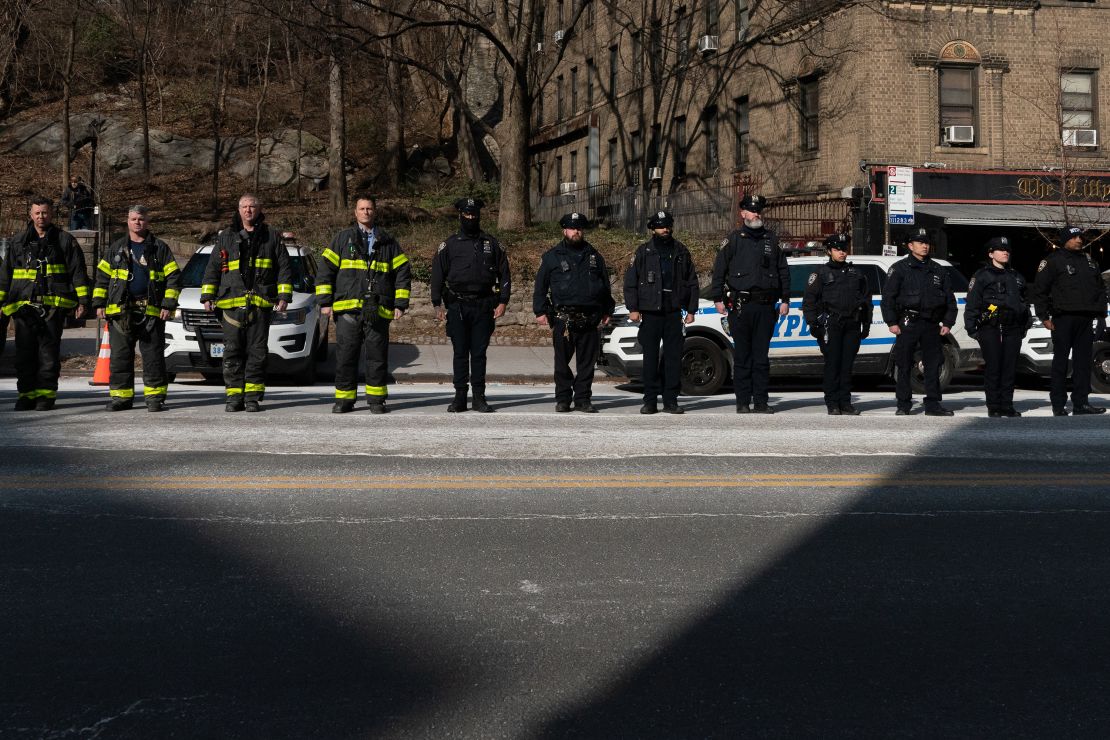 New York City police officers and firemen stand at attention as they await the remains of Police Officer Jason Rivera to be brought to the funeral home on January 23 in New York City. 