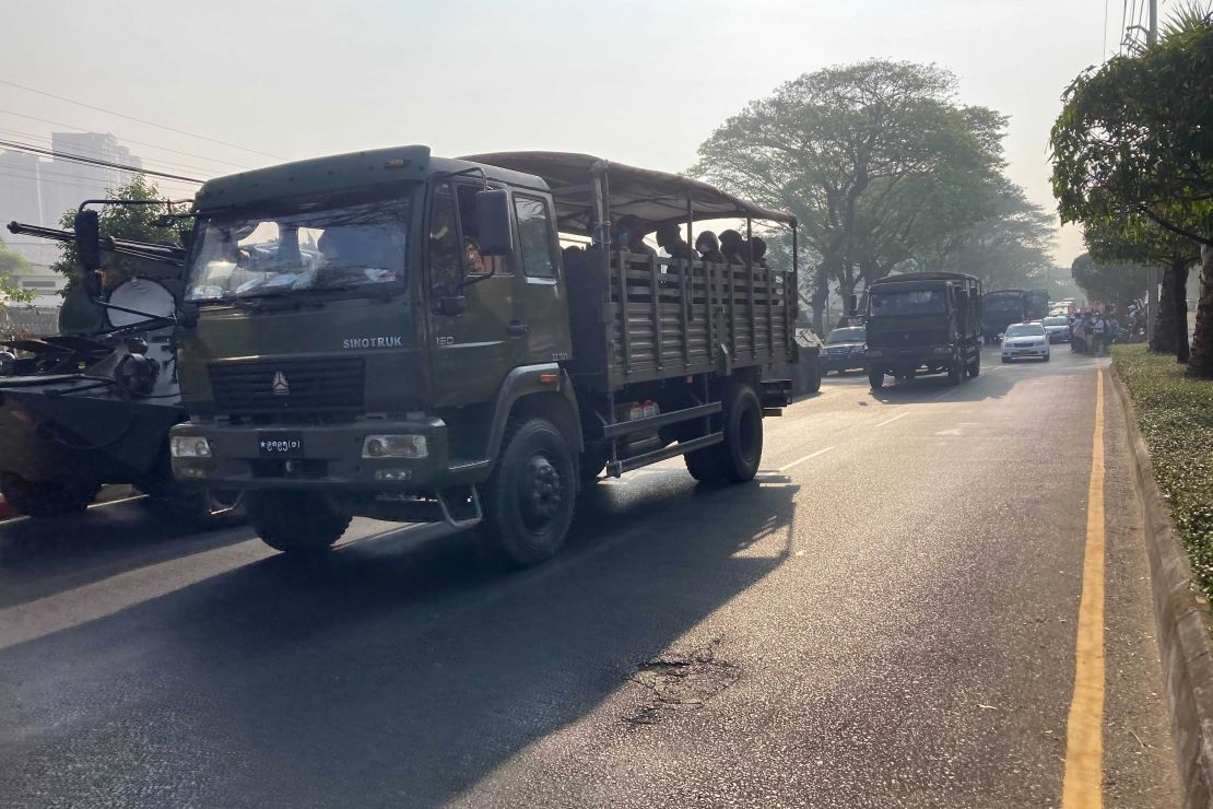 A convoy of military trucks with soldiers drives past armored personnel carriers deployed outside the Central Bank building in Yangon, Myanmar on February 15, 2021. 
