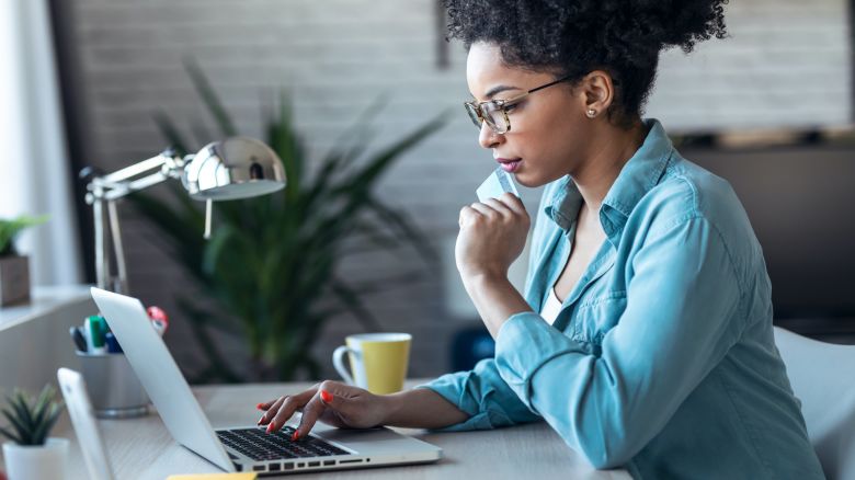 underscored best day to book flights lead woman on laptop