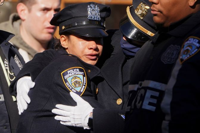 Police officers hug after Mora's casket arrived at a funeral home on January 26.