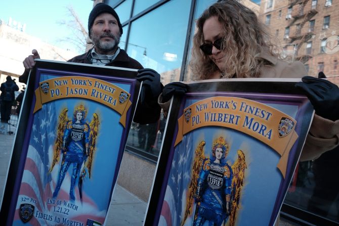 People pay tribute to Mora and Rivera as they watch Mora's body be moved to a funeral home.