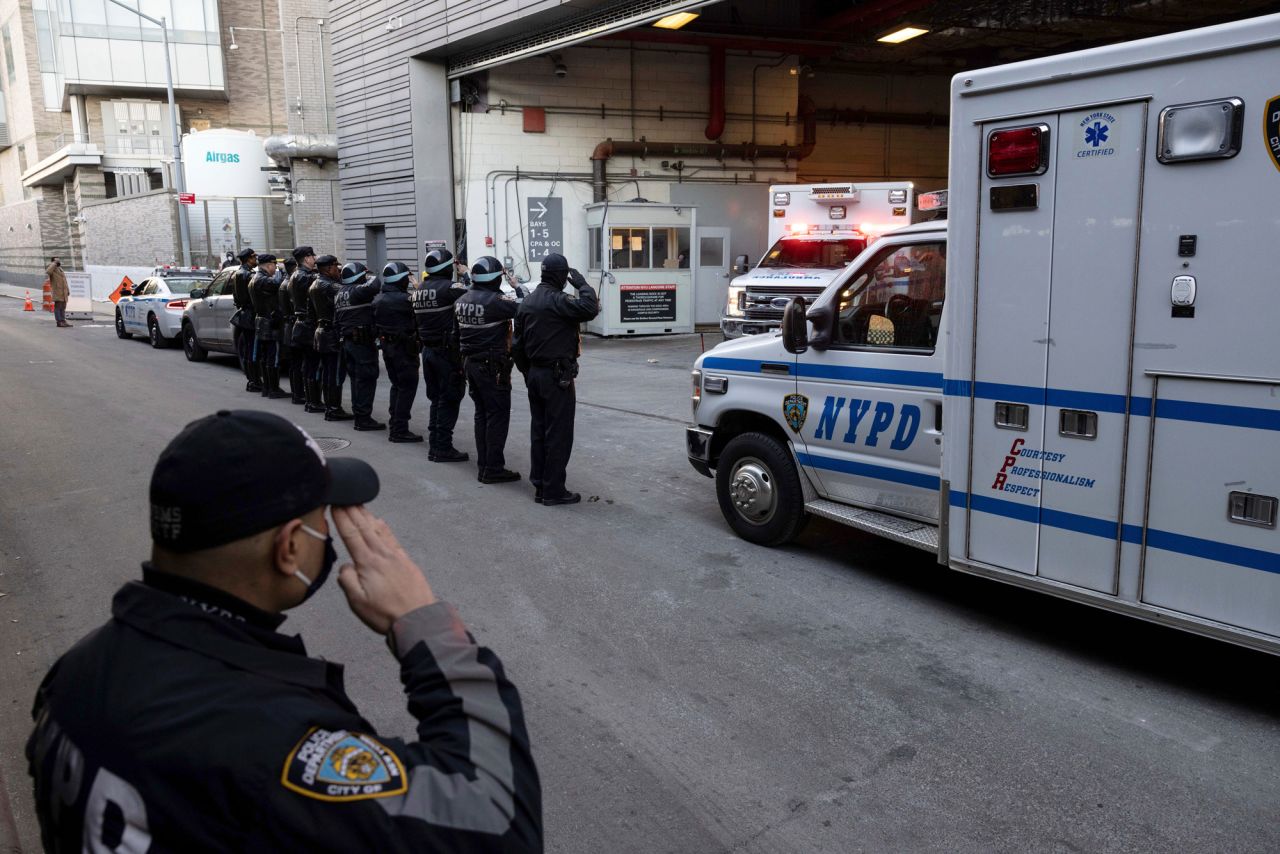 Police officers salute as Mora's remains are transferred outside a New York City hospital on January 25.