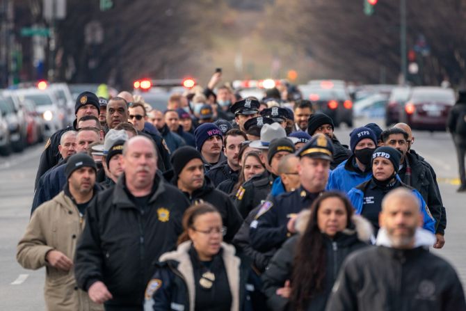 Police officers walk from the 32nd Precinct to Harlem Hospital, near the scene where the two officers where shot.