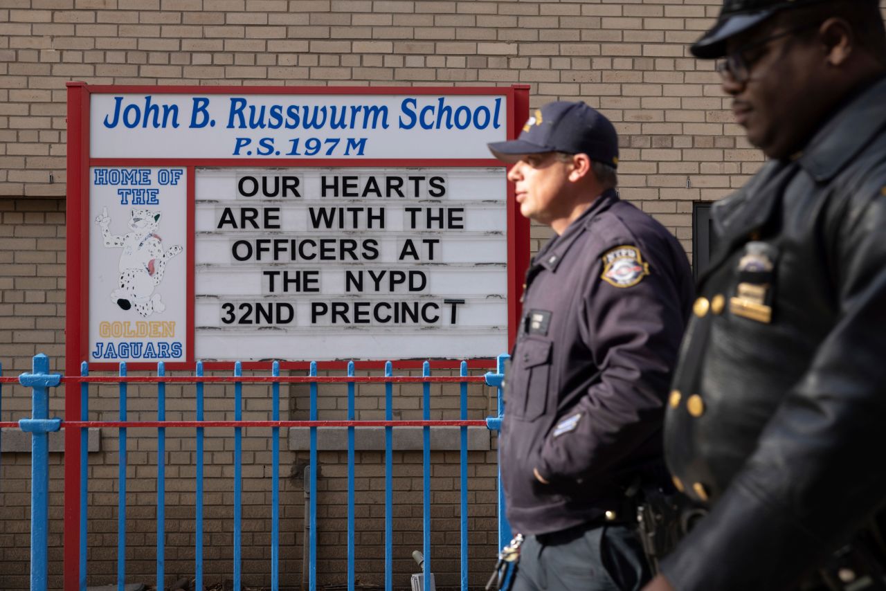 Police officers walk past a sign with a message of support.