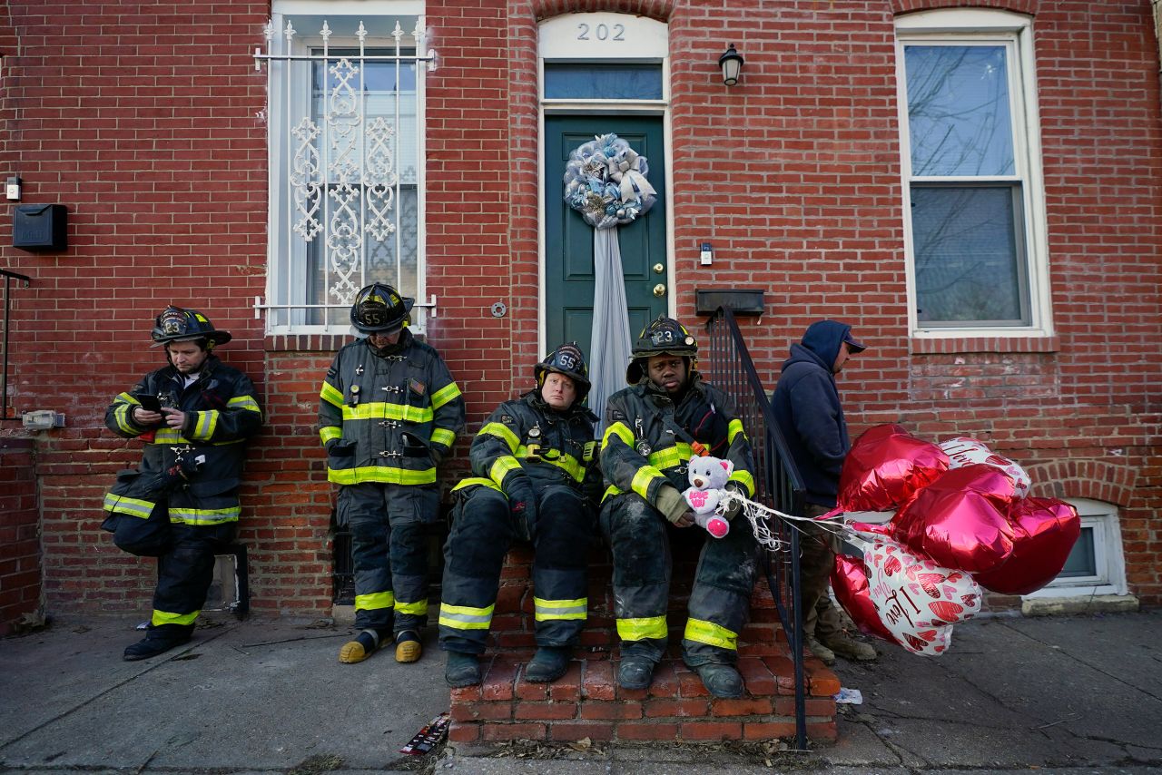 Baltimore firefighters sit on a stoop across the street from a vacant row home where <a href="https://www.cnn.com/2022/01/24/us/maryland-firefighters-dead-row-home-fire/index.html" target="_blank">several firefighters died in a building collapse</a> on Monday, January 24. The firefighter on the right is holding balloons that were given to him by a local resident.