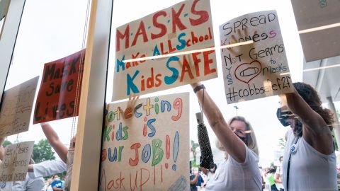 Pro-mask demonstrators hold signs during a rally over the Cobb County School District's optional mask policy on August 19, 2021, in Marietta, Georgia.