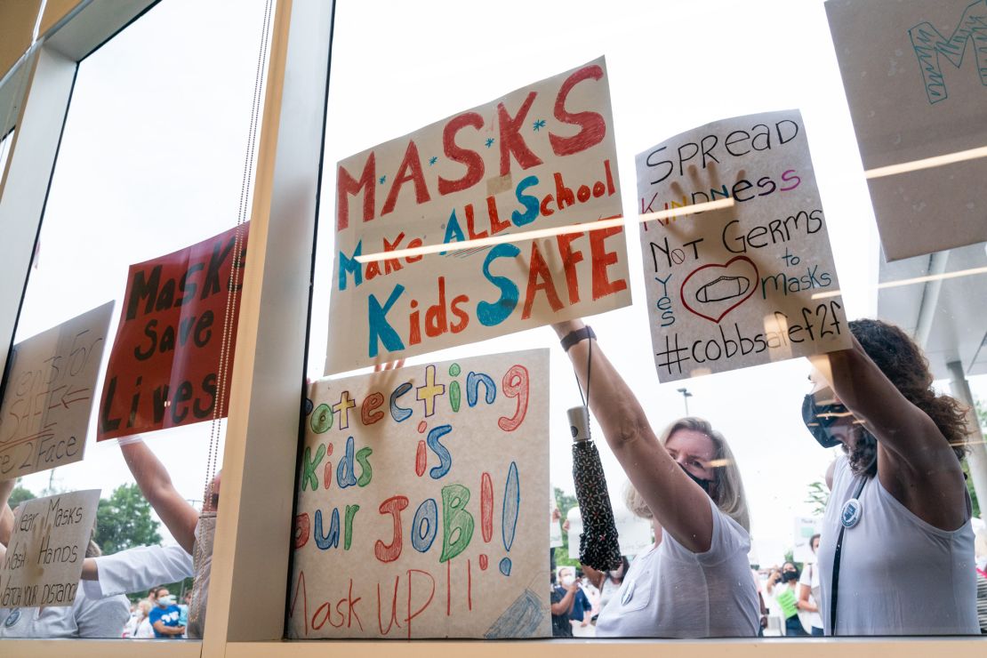 Pro-mask demonstrators hold signs during a rally over the Cobb County School District's optional mask policy on August 19, 2021, in Marietta, Georgia.