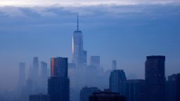 Fog shrouds the skyline of lower Manhattan and One World Trade Center behind buildings in the Newport neighborhood of Jersey City, New Jersey, as the sun rises in New York City on January 25, 2022, seen from Jersey City.
