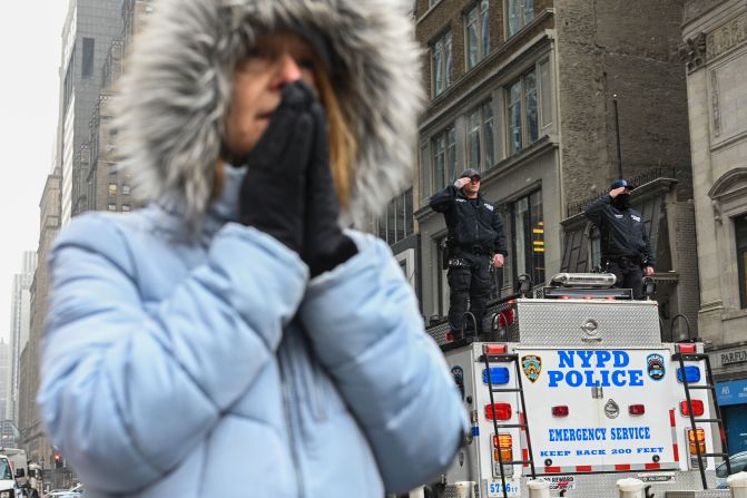 Police officers salute Rivera's funeral procession near a praying woman. 