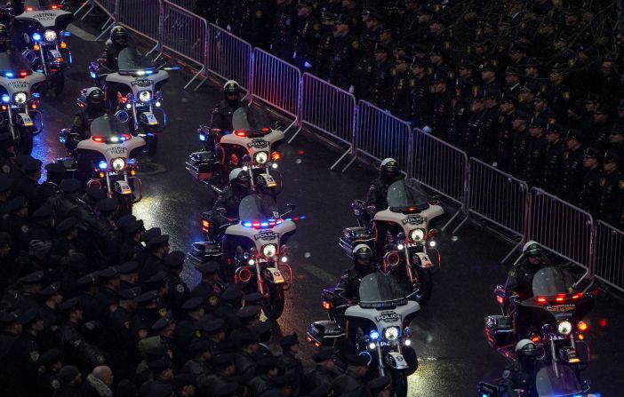 Police officers on motorcycles accompany Rivera's hearse.