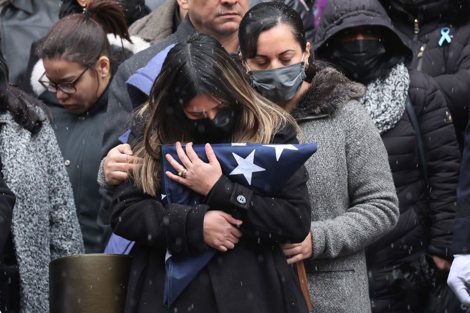 Rivera's wife, Dominique, holds a flag from his casket.