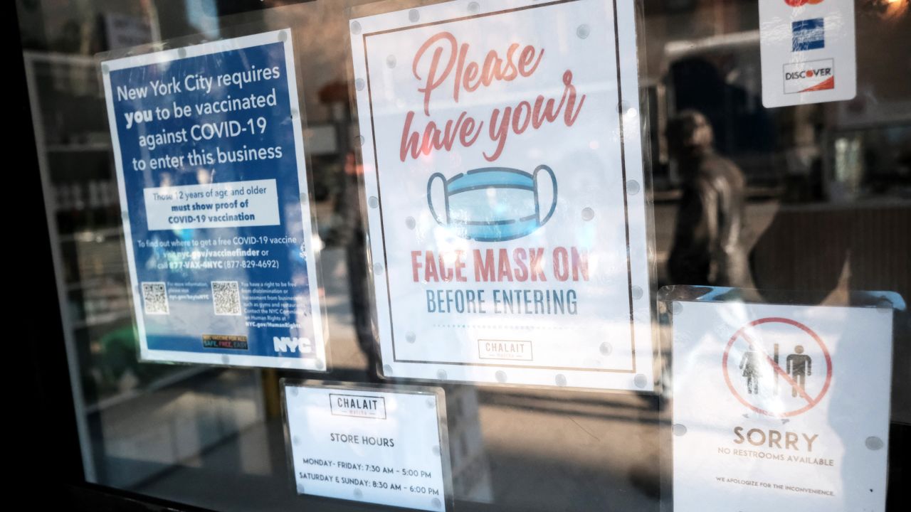A sign on the door of a coffee shop in Manhattan ask for proof of vaccination and the wearing of a mask on the day that a mask mandate went into effect in New York on December 13, 2021 in New York City. As parts of New York are seeing a surge in Covid cases, New York Governor Kathy Hochul has enacted a new mask mandate with fines up to $1,000 per violation.
