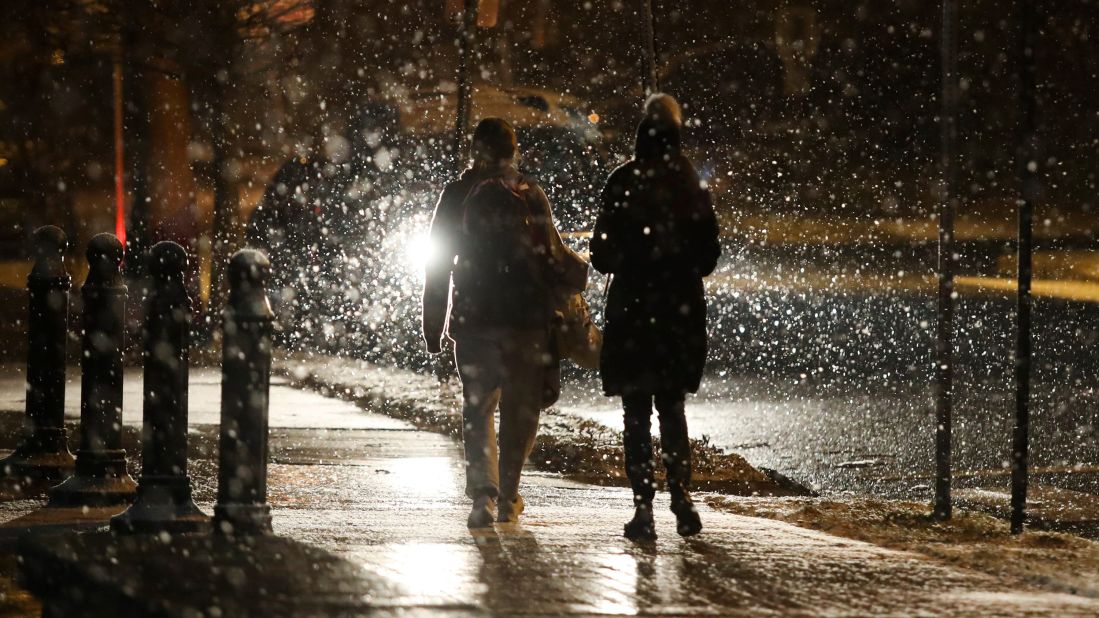 People walk in snowfall on Friday, January 28, in Wilmington, Delaware.