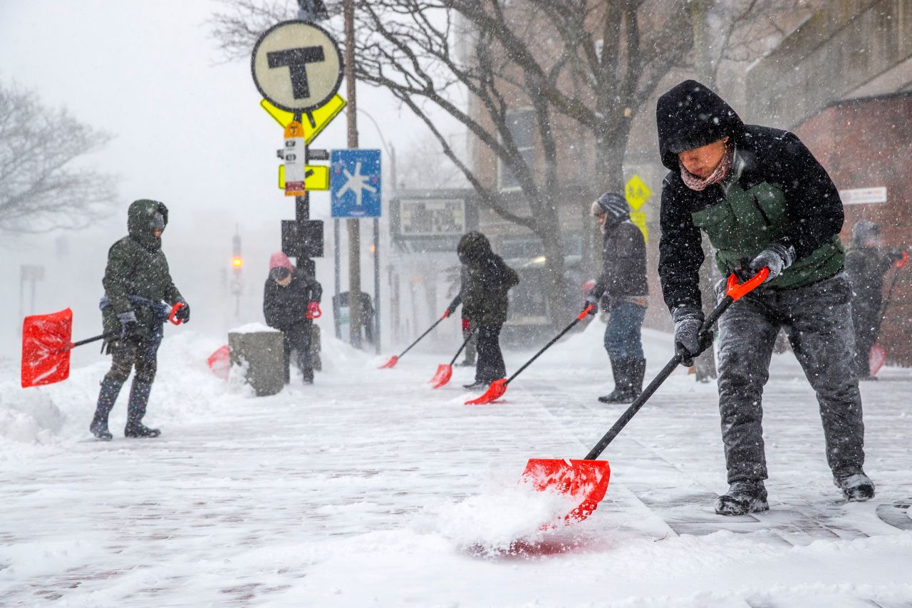 People shovel outside of the Davis Square MBTA station in Somerville, Massachusetts.