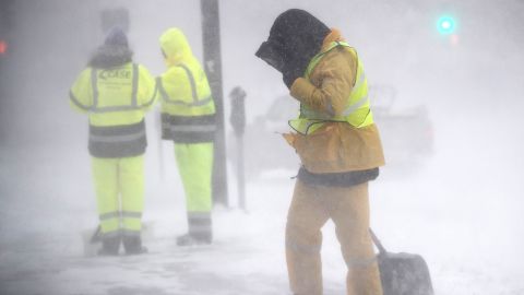A worker shields himself from blowing snow Saturday in Boston.