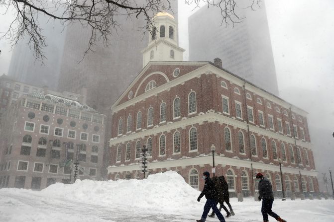 People walk in the snow outside Faneuil Hall, Saturday, in Boston, Massachusetts.