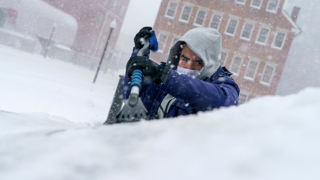 Xavier Martinez scrapes snow off his windshield in Providence, Rhode Island, on Saturday, January 29.